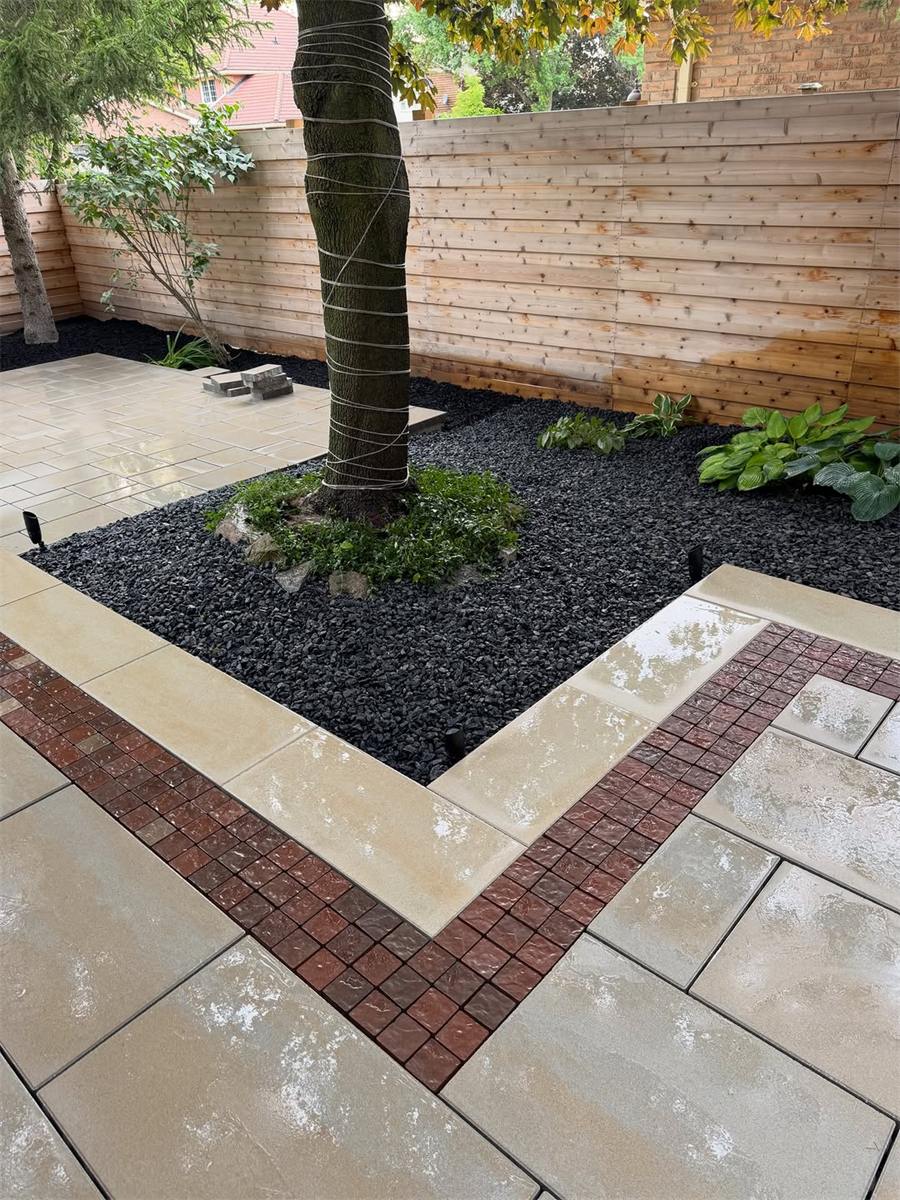 Slab patio with a red brick border around a tree bed