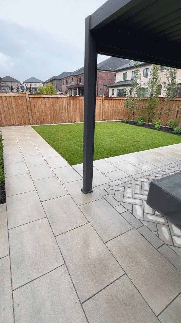 Porcelain patio under a pergola beside a new lawn