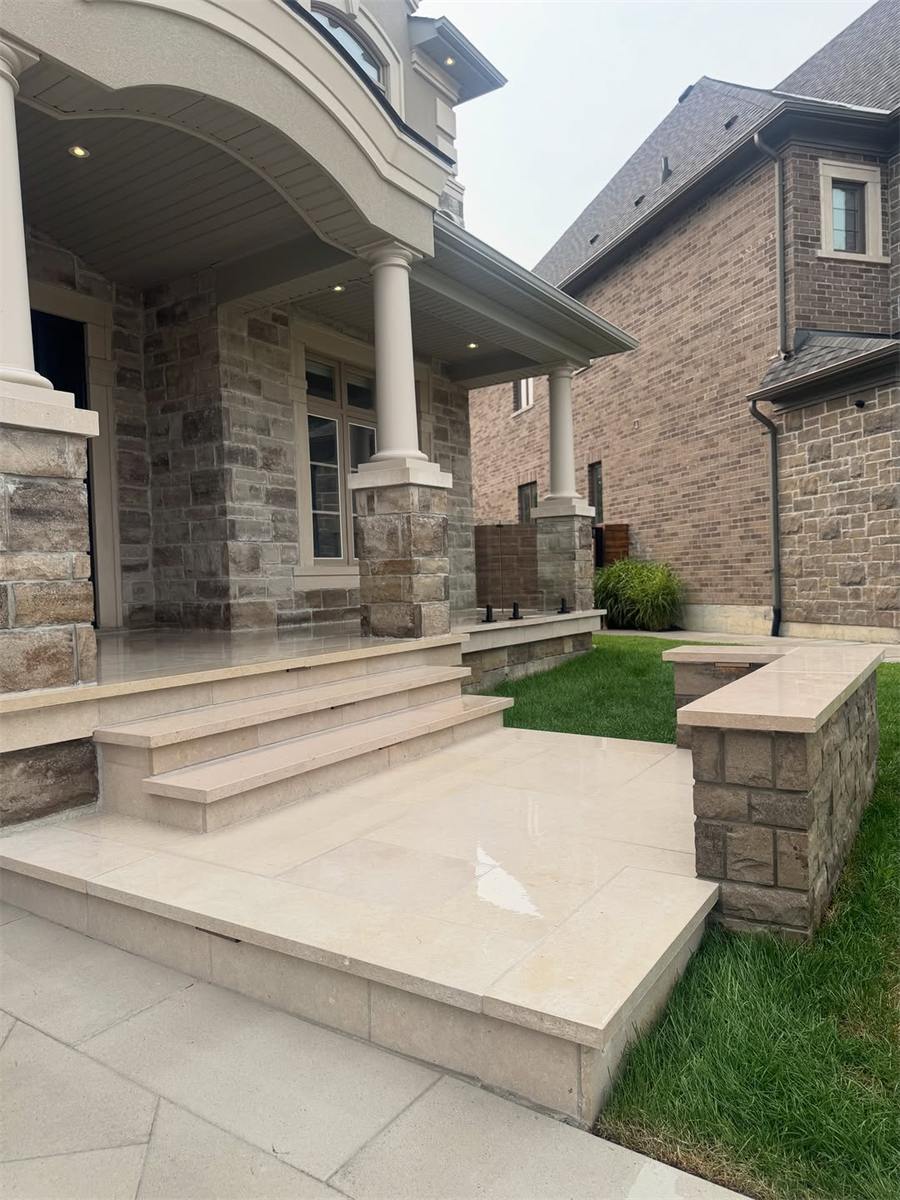 Front porch steps and landing in light slabs with stone pillars